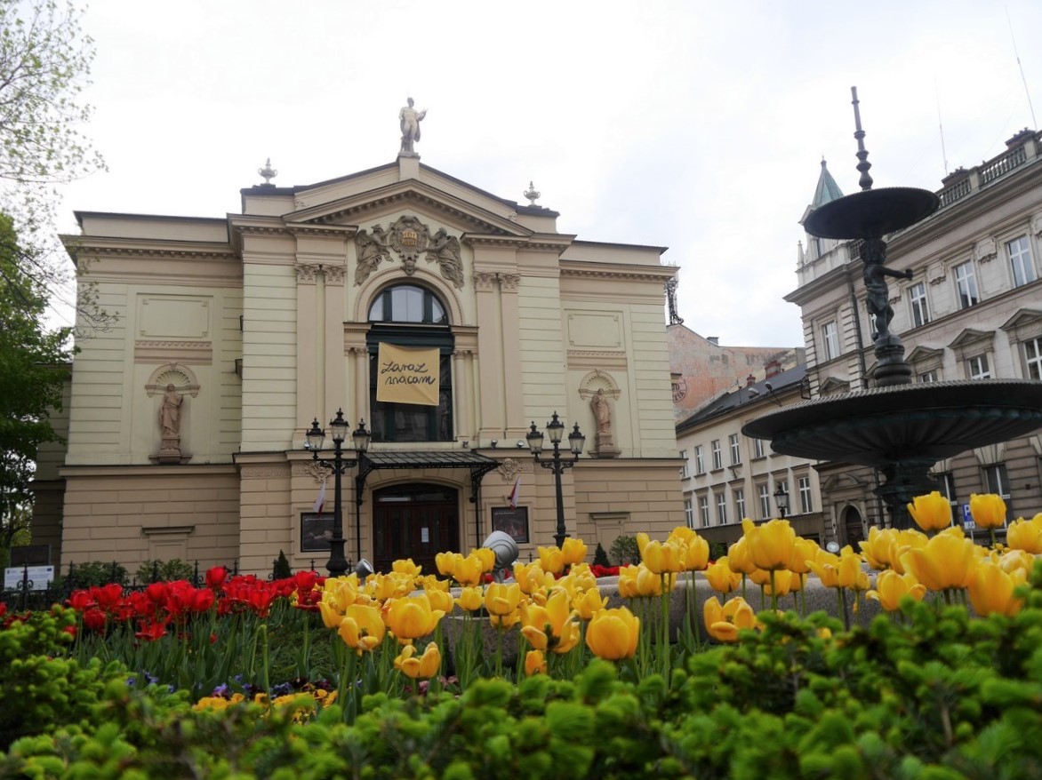 Na pierwszym planie kwietnik, na drugim - fontanna i budynek Teatru Polskiego