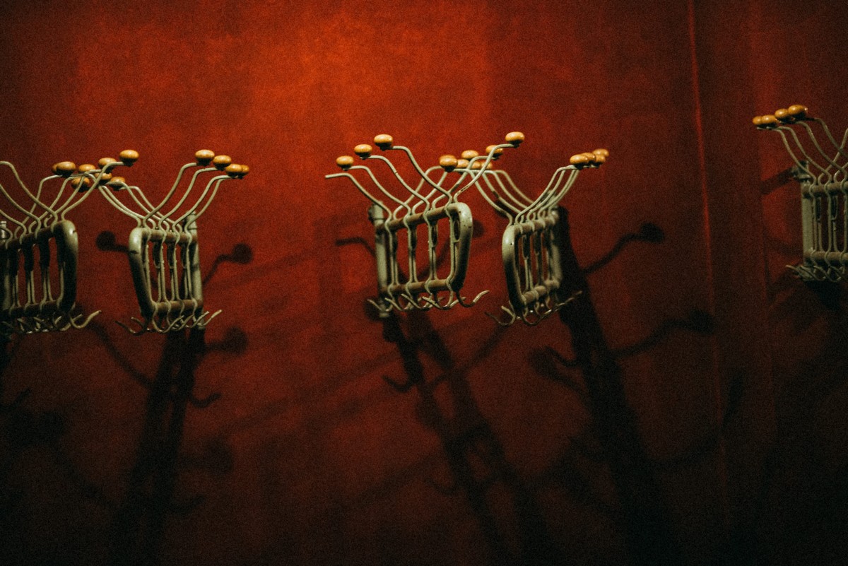 Kilka metalowych wieszaków w stylu retro na ciemnoczerwonej ścianie w teatralnej szatni. 
