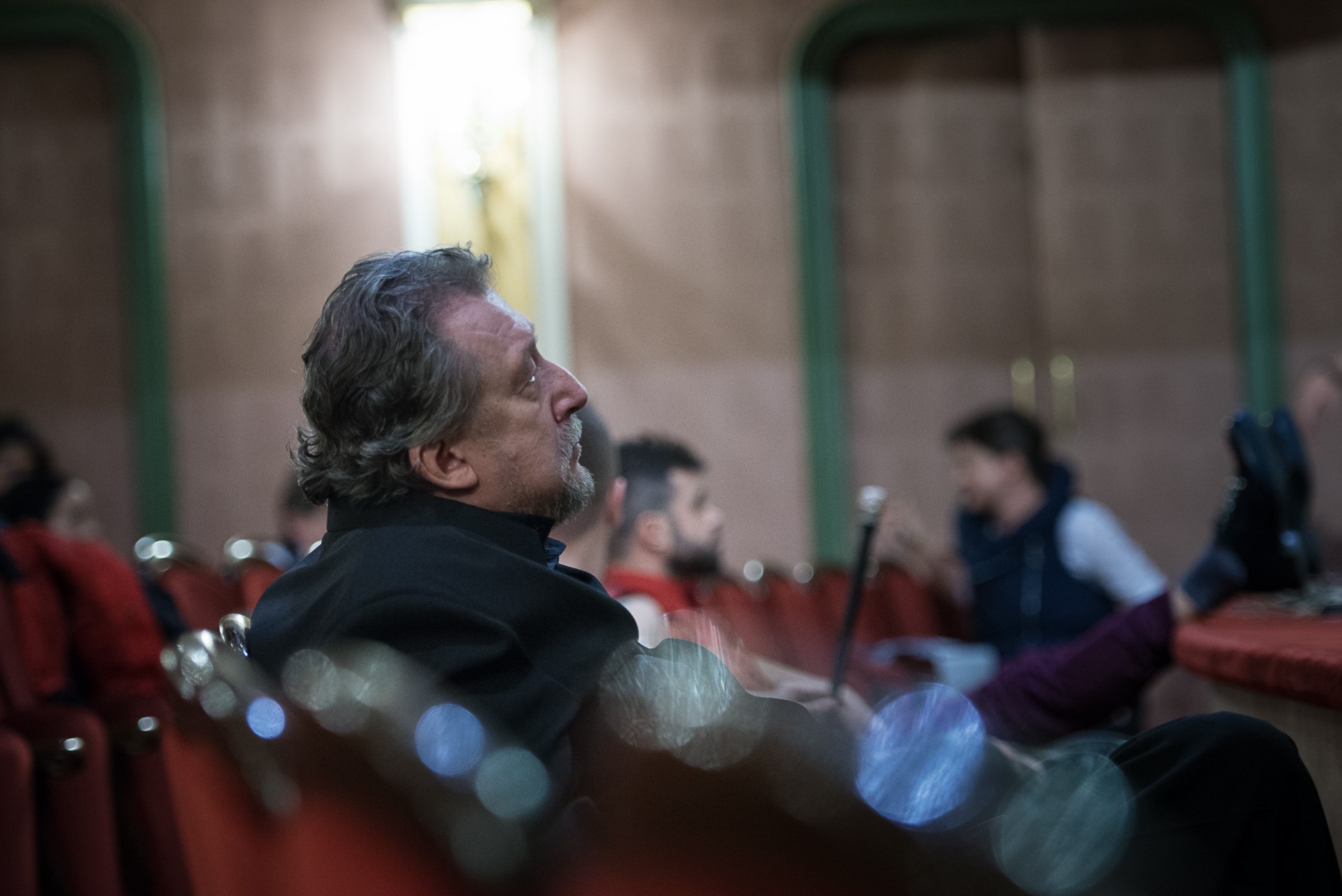 Na zdjęciu - starszy aktor, Kazimierz Czapla siedzi na widowni teatru. Patrzy przed siebie w zamyśleniu. 