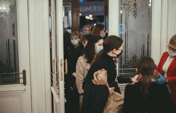 Na zdjęciu kilku widzów w maseczkach ochronnych wchodzi do teatru przez wejście główne. 