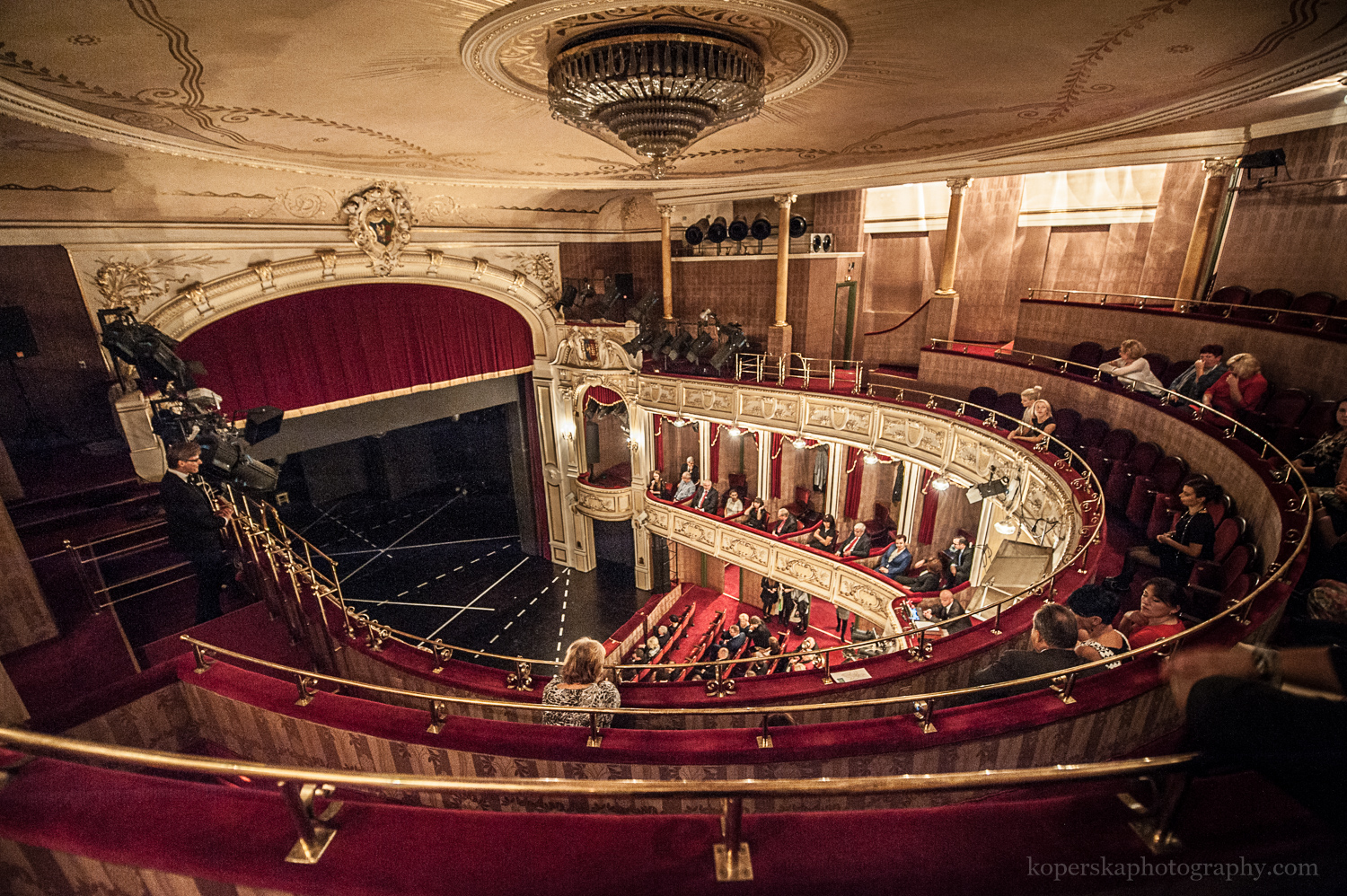 Widownia teatru pokazana z góry, z drugiego balkonu. Zabytkowe wnętrze ze złotymi zdobieniami i bordowymi fotelami. 